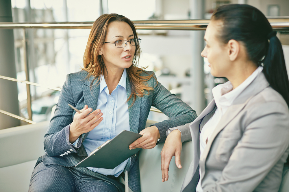 Two women talking on a couch in a professional setting