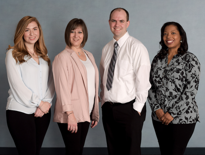 three women and a man that HR Consultants standing in professional dress smiling for the camera