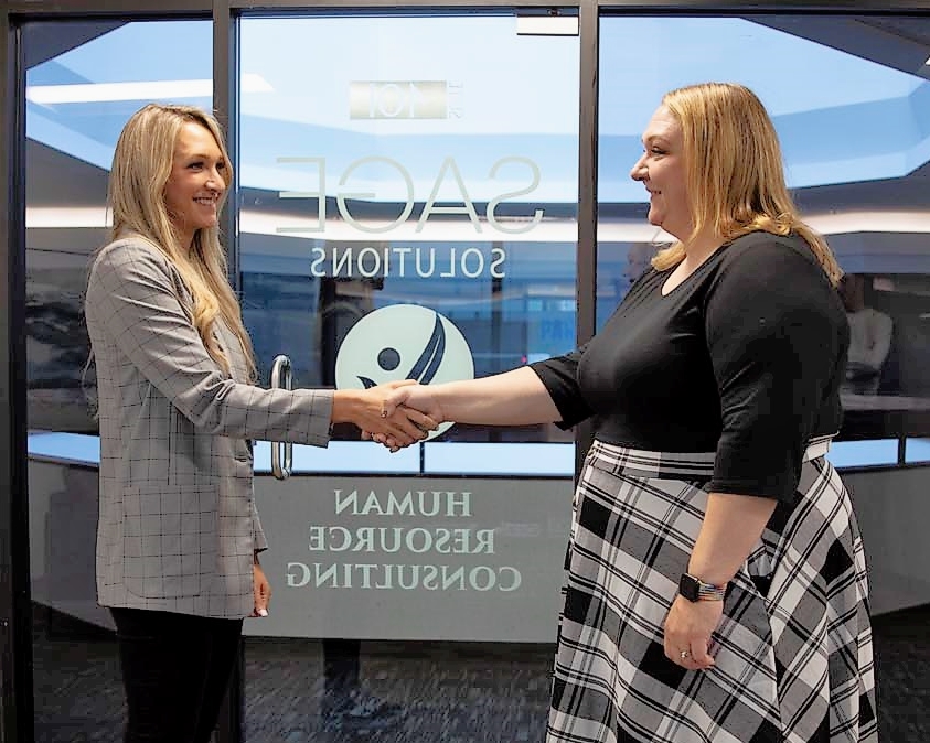 two blond women at Sage Solutions Group shaking hands