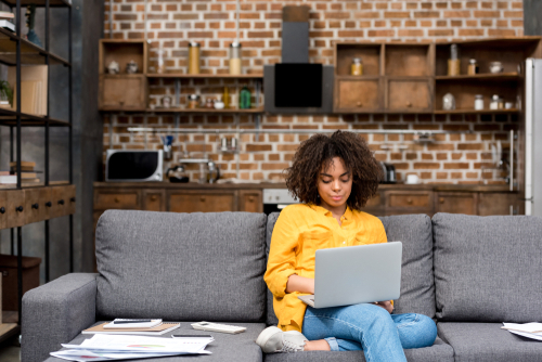 woman working home office in a laptop sitting on her couch
